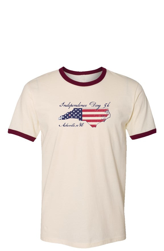Cream t-shirt with red cuffs and collar featuring an outline of north Carolina filled with parts of the American flag. The graphic is surrounded by 'Independence Day 5k' and 'Asheville, NC' in ornate text