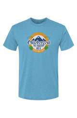 blue t-shirt with Oktoberfest Half Marathon & 5k logo with blue mountains, green hops in a gold ring on a white background