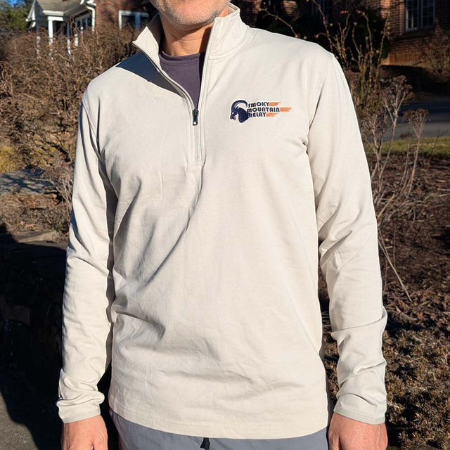 Person wearing a light gray pullover with a Smoky Mountain Relay speed ram logo on the chest outdoors.