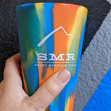 Colorful silicone pint glass with 'SMR Smoky Mountain Relay' logo held by a hand.