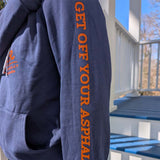 Blue hoodie with orange text 'GET OFF YOUR ASPHALT' on a person outdoors.