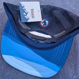 Blue and gray cap with a brand tag on a textured surface