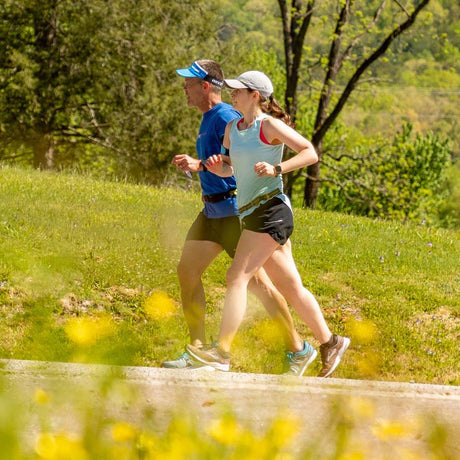 Two people jogging on a path with greenery and trees in the background